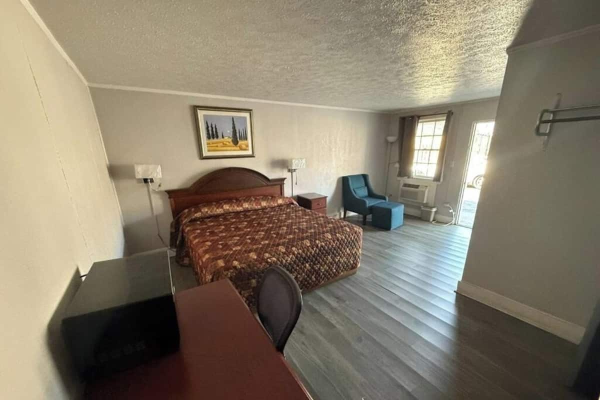 A room with a bed, a desk, a chair, and a window.