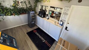 A room with a reception desk, an ATM, a door, and a black doormat with 'economyinn' text.