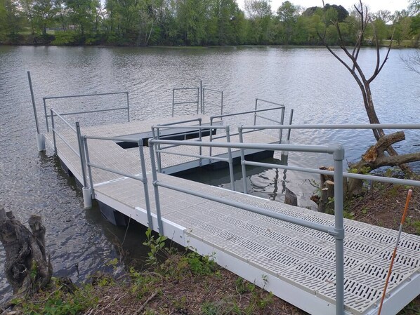 A metal dock with a metal railing and a small platform extending into a body of water.