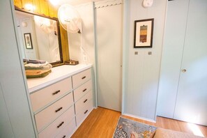 A bathroom with a mirror, a sink, a towel rack, and a framed picture on the wall.