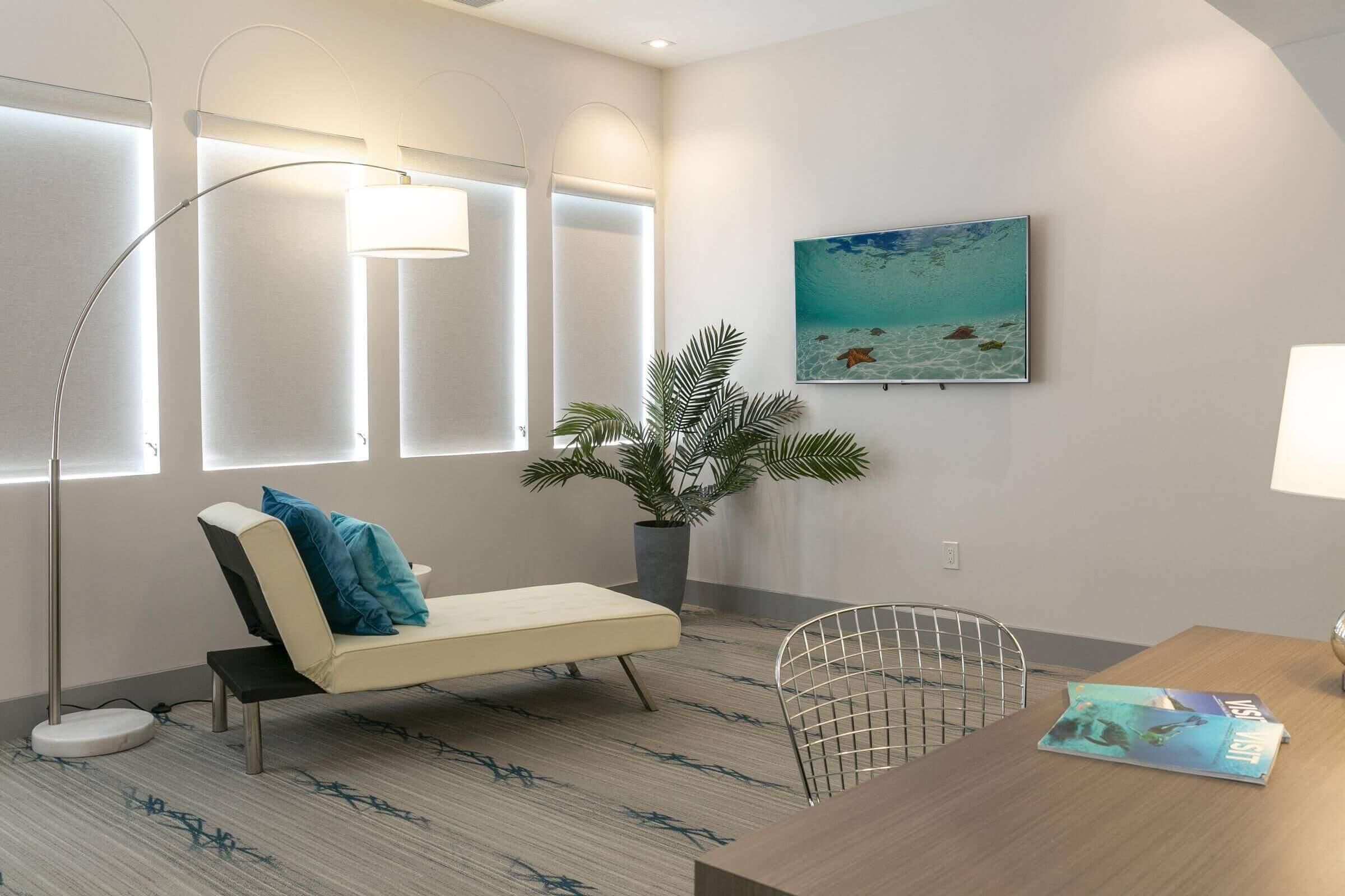 A modern room with a sofa, a dining table, a potted plant, and a wall-mounted painting.