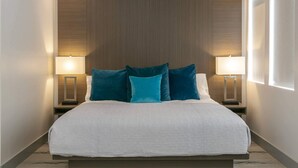A neatly made bed with a white quilt, two side tables with lamps, and a wooden headboard. - Suite 4, 10% Off Fall Stays (Cruz Bay)