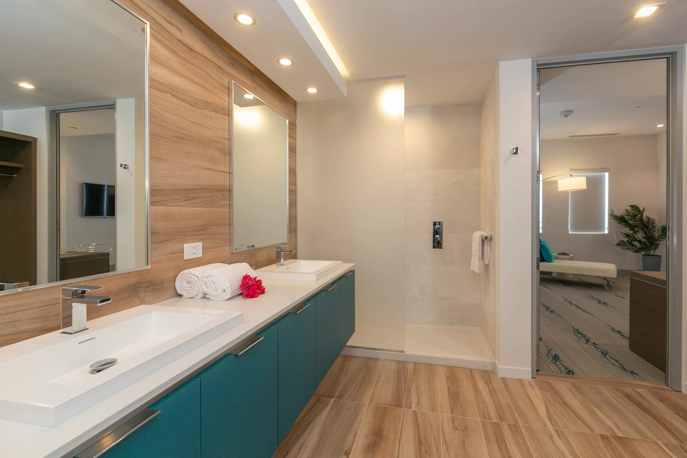 Ein modernes Badezimmer mit zwei Waschbecken, einer Dusche und einem großen Spiegel.