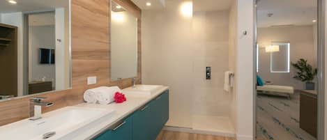 Ein modernes Badezimmer mit zwei Waschbecken, einer Dusche und einem großen Spiegel.