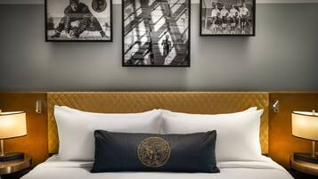 Una habitación de hotel con una cama, dos lámparas de noche, un cabecero y tres cuadros en la pared.