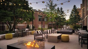 An outdoor patio with seating, a fire feature, and string lights. - The Union Club Hotel at Purdue University, Autograph Collection (West Lafayette)