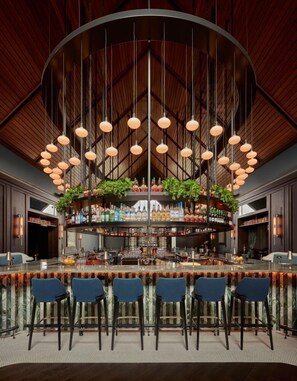 A bar area with a curved ceiling, hanging pendant lights, and a bar counter with stools. - The Union Club Hotel at Purdue University, Autograph Collection (West Lafayette)