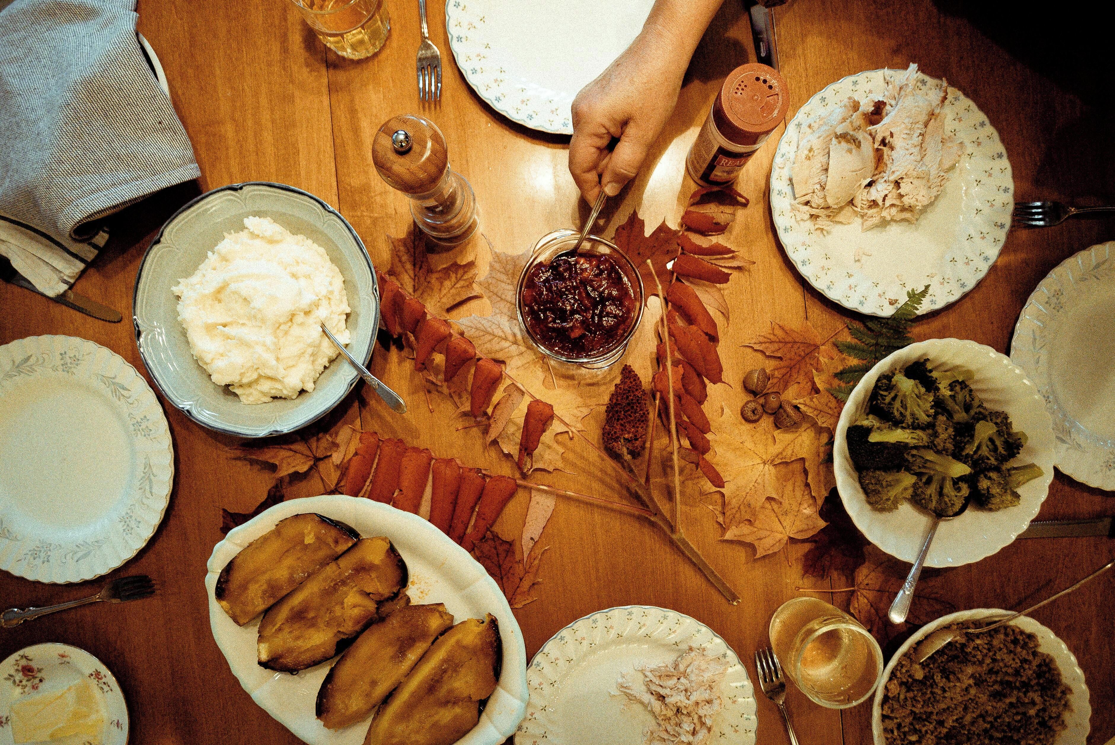 A dining table with various dishes, utensils, and a person serving food.
