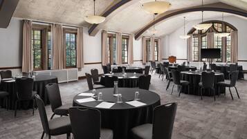 A conference room with round tables, chairs, and a large screen.