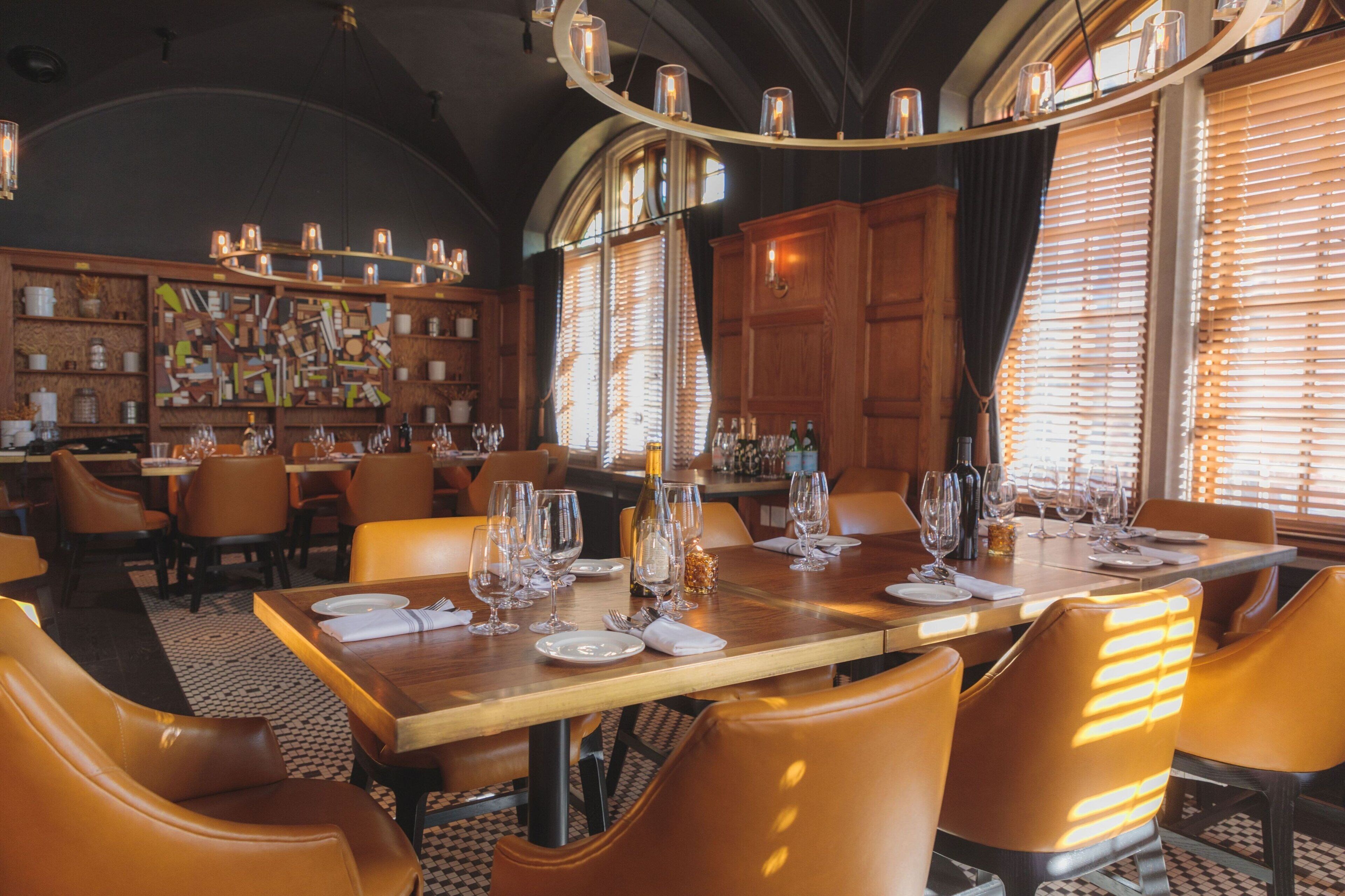 Un restaurante con una larga mesa de madera dispuesta para comer, rodeada de sillas de cuero.