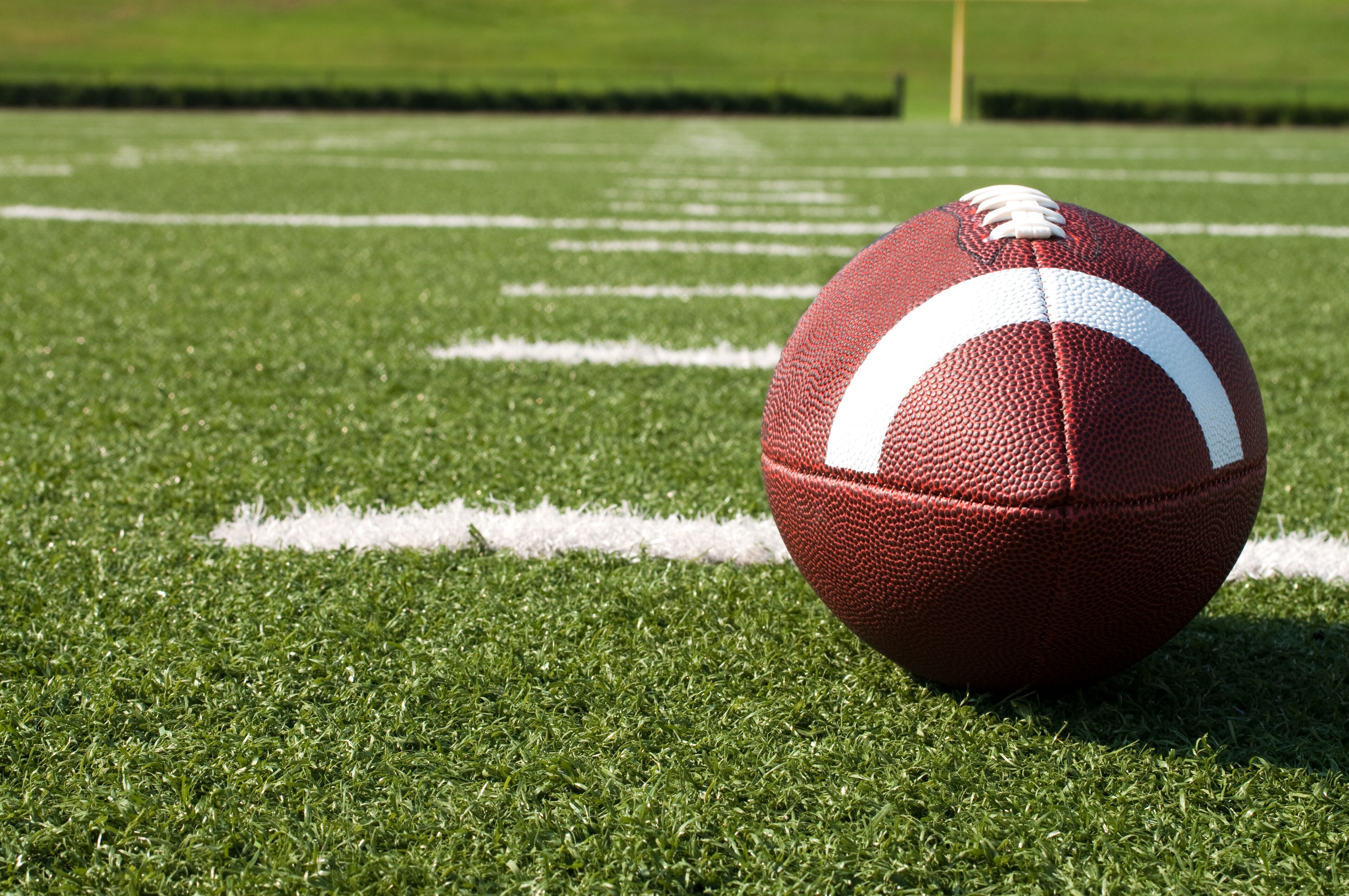 A football on a green field with white lines.