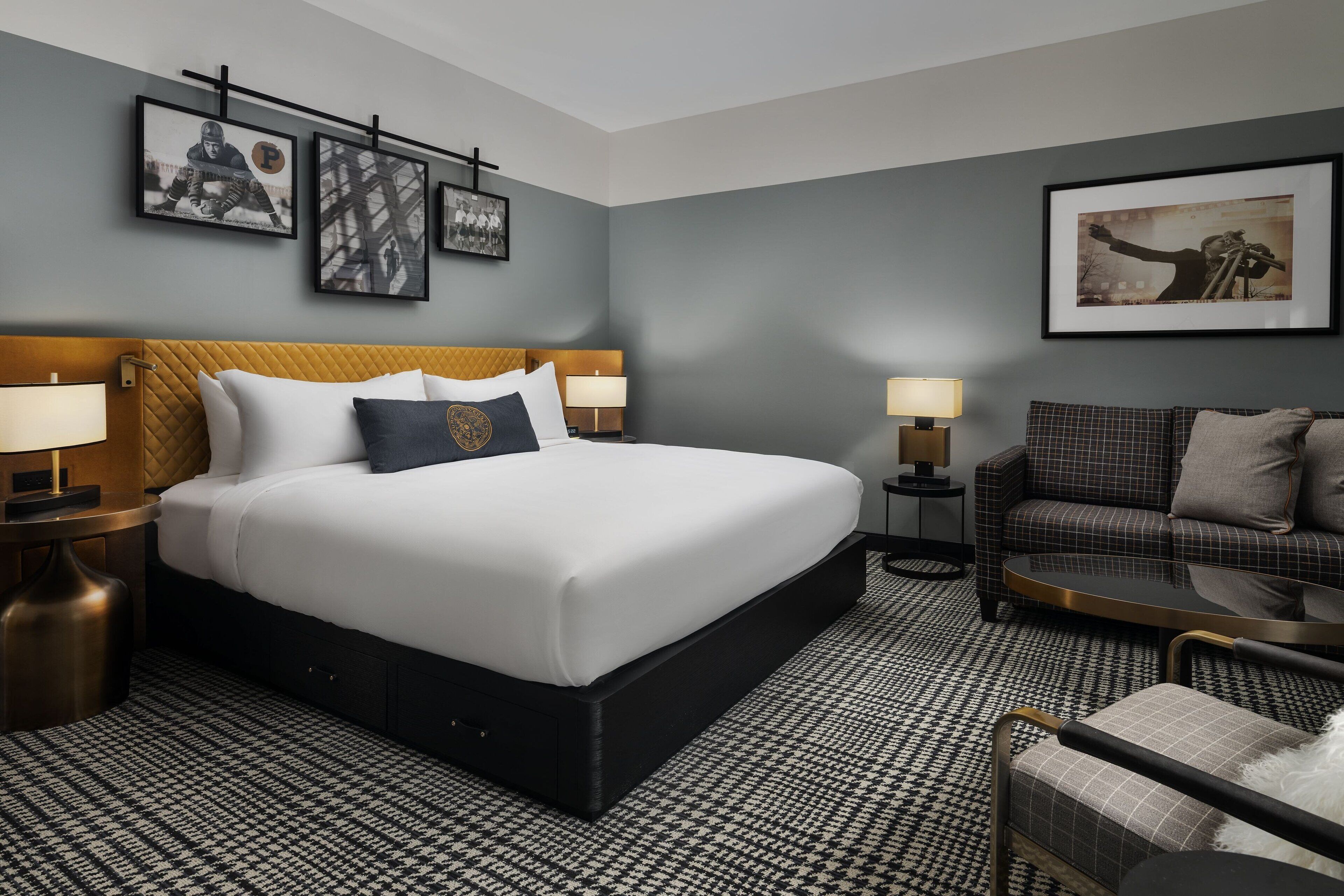 A hotel room with a large bed, a sofa, a coffee table, and wall art.