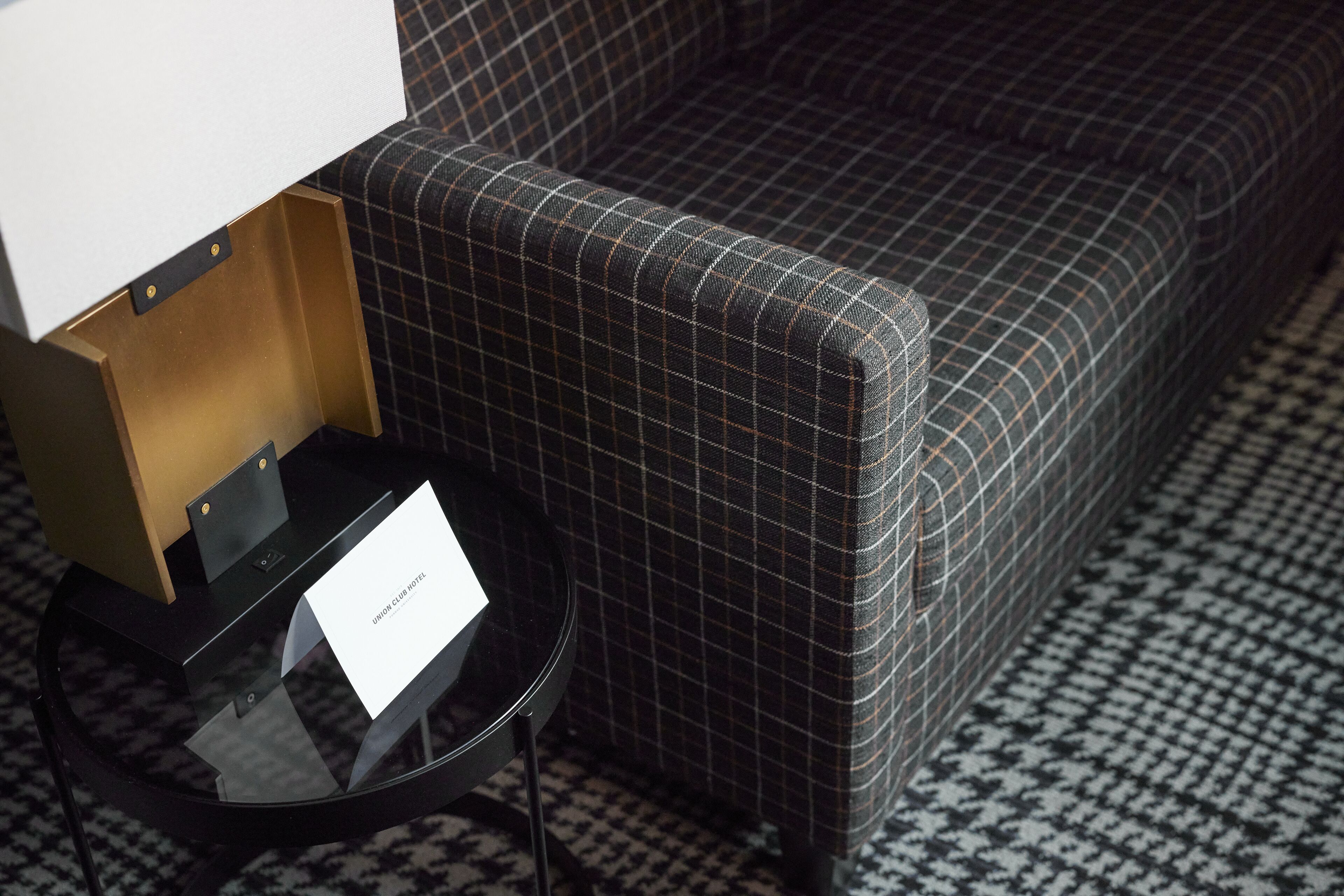 A check-in area with a black and white checkered floor, a black table with a glass top, and a sign that reads "Union Club Hotel."