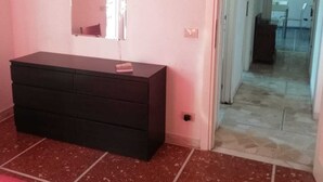 Una habitación con un aparador de color oscuro, un espejo encima y piso de baldosas.