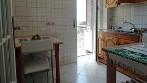 Una cocina con salpicadero de azulejos, armarios de madera, un lavabo y un comedor con mesa y sillas.