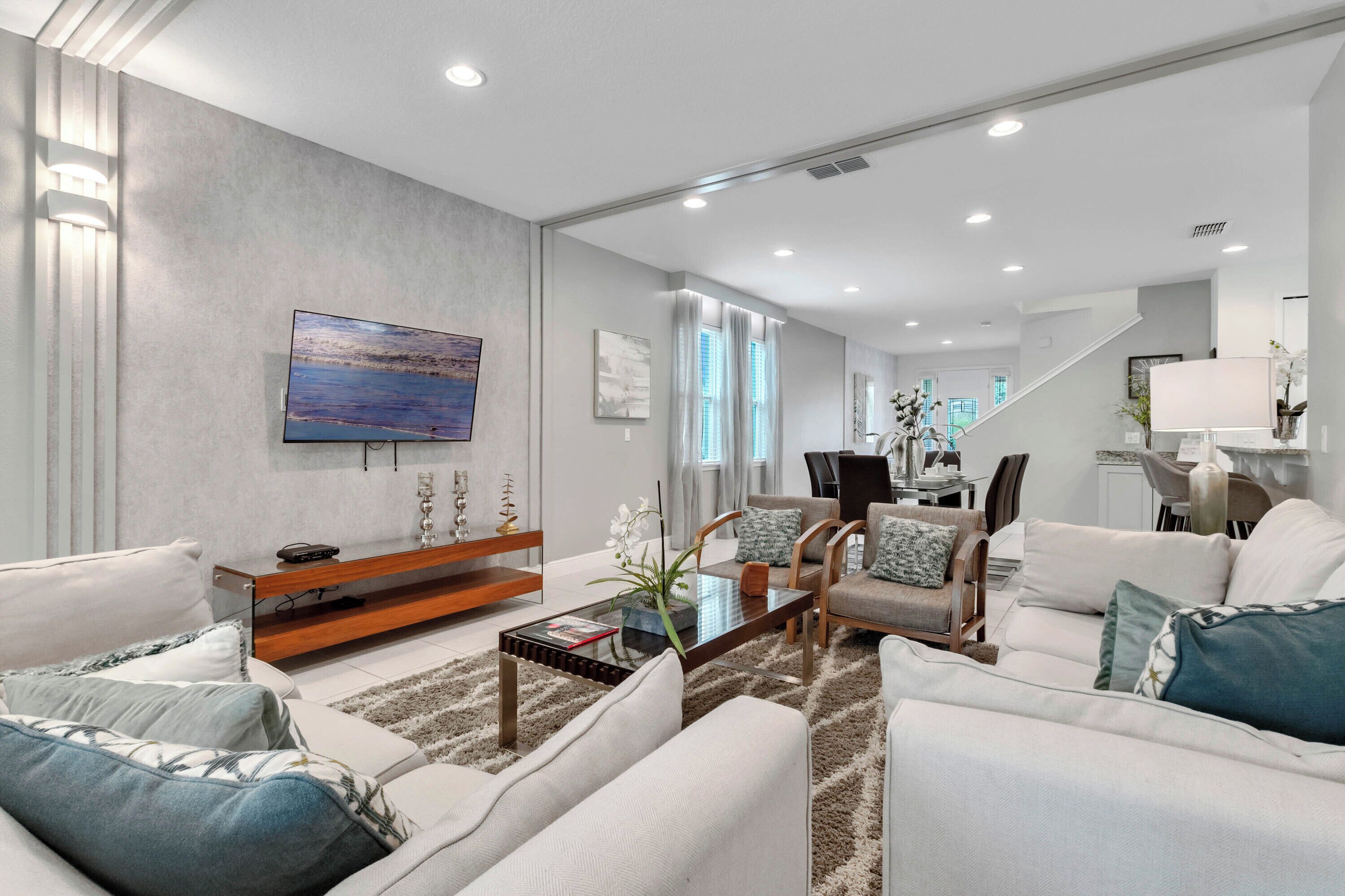 A modern living room with a flat-screen TV, a coffee table, sofas, and a staircase leading to another level.