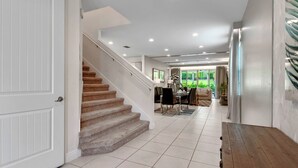 A hallway with a staircase, a dining area, and a view of the outdoors. - 6 Bedrooms/ 6.5 Bathrooms/ Encore (7514 MA) (Kissimmee)