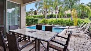 A covered patio with a pool, outdoor furniture, and a view of a landscaped garden. - 6 Bedrooms/ 6.5 Bathrooms/ Encore (7514 MA) (Kissimmee)