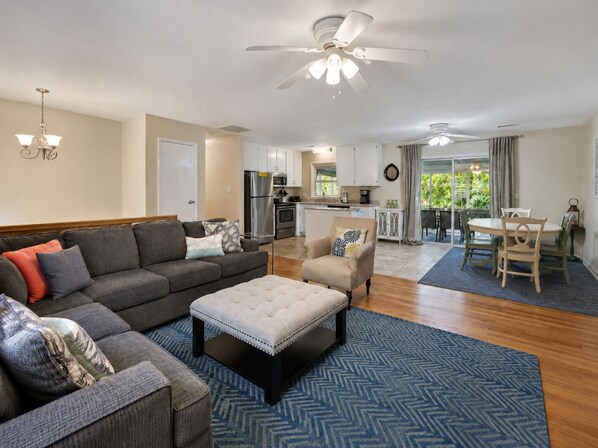 A spacious living area with a sofa, ottoman, and a dining table with chairs.