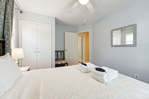 Una habitación de hotel con cama, mesita de noche, silla, armario y espejo en la pared.