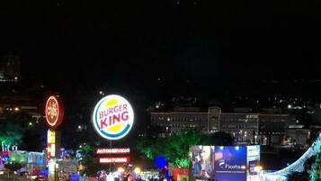 Un cartello Burger King con un grande logo illuminato, un cartello Chili's e una pubblicità di Ficoha.