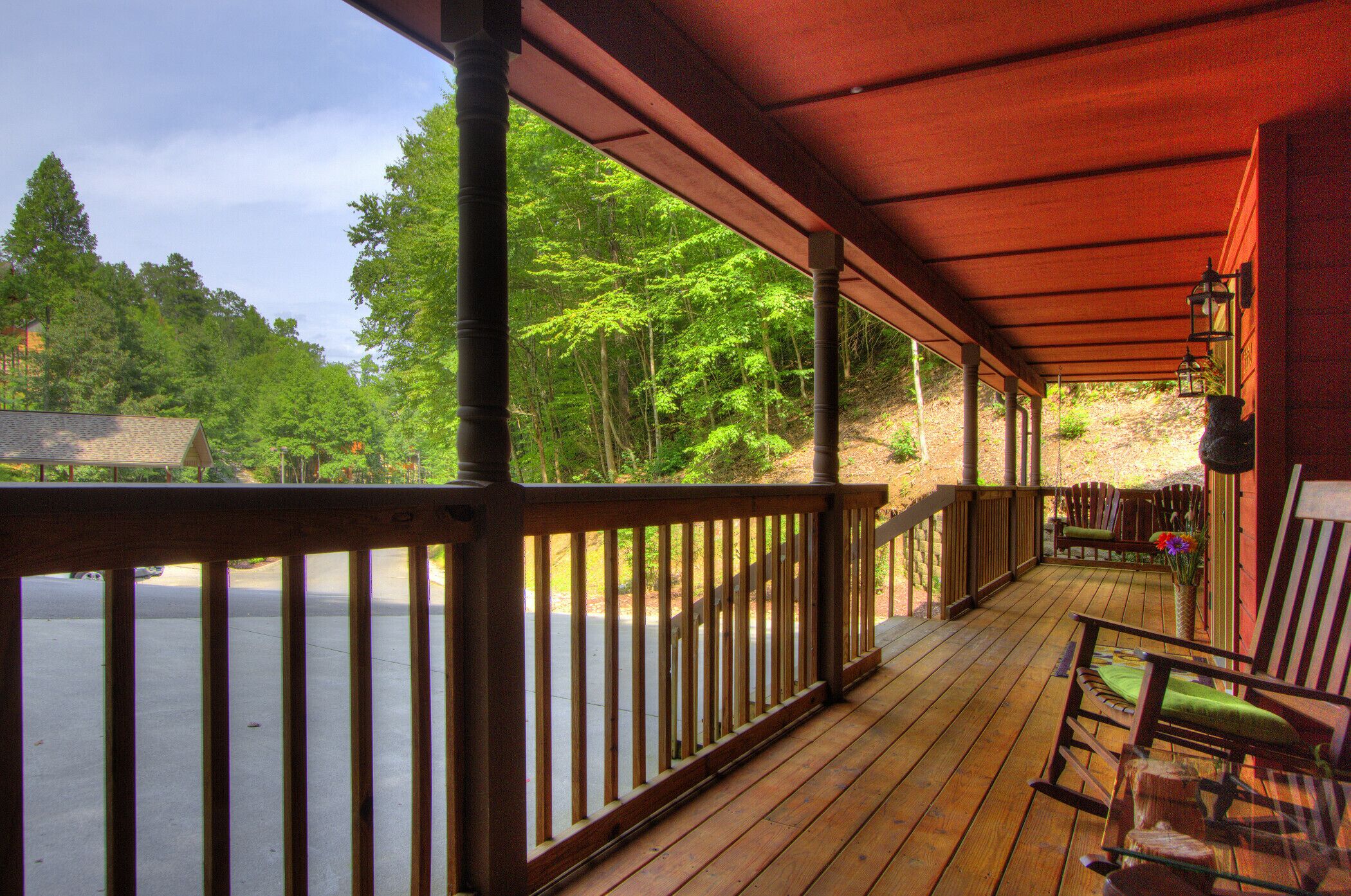 A wooden deck with a view of a forest and a lake.