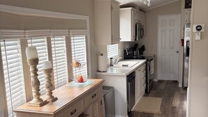 A kitchen with wooden cabinets, a countertop, and a window with blinds. - Newly renovated, large deck, backs onto large pond (Sarasota)