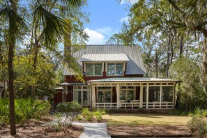 A two-story house with a covered porch, surrounded by trees and a well-maintained lawn.