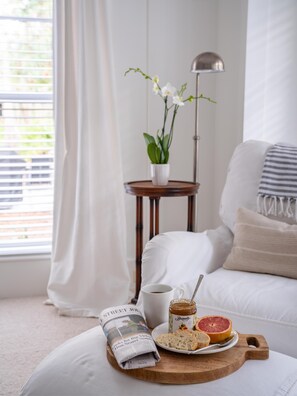 A cozy room with a bed, a small table with a plant, a lamp, and a tray with breakfast items.