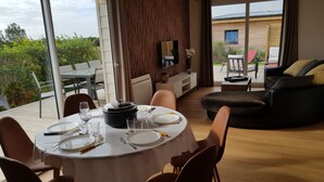 Un comedor con una mesa redonda para cuatro personas, un sofá y un televisor montado en la pared.