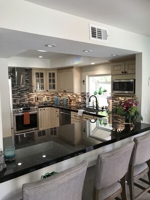 A modern kitchen with a central island, stainless steel appliances, and a view to the outdoors. - SPECIAL RATE Private Pool  2 master suites townhome in Private Club Palm Desert (Palm Desert)