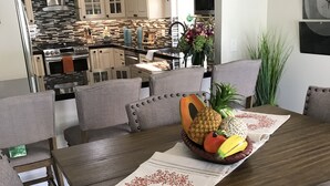 A dining area with a wooden table, grey upholstered chairs, and a decorative centerpiece.