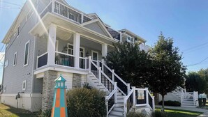 A two-story house with a front porch, a staircase, and a small orange and green lighthouse-like structure. - 4 BR/ 4 BA/ Single Family - 2 Primary Suites (Ocean City)