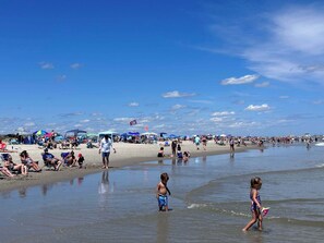 A crowded beach with people relaxing and children playing in the water. - 4 BR/ 4 BA/ Single Family - 2 Primary Suites (Ocean City)