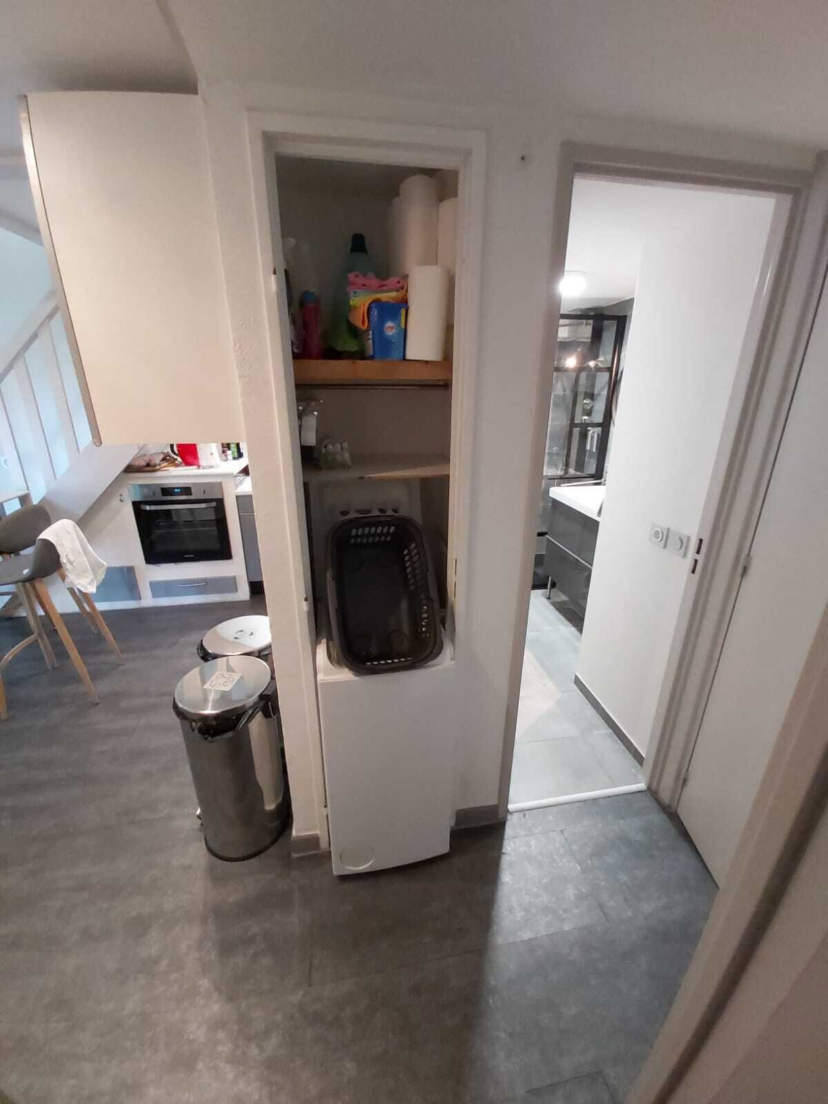 Una cocina compacta con horno integrado, un refrigerador pequeño y un cubo de basura.