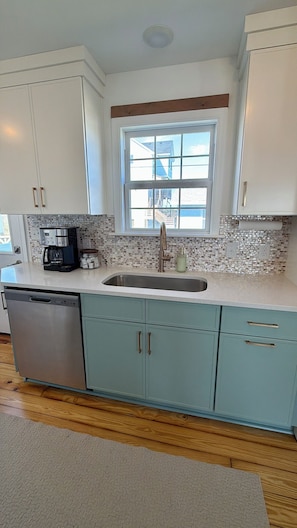A kitchen with a window, a coffee maker, and a dishwasher.