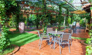 An outdoor patio with brick flooring, metal chairs, and tables. - Elwood Premier Resort Phu Quoc (Phu Quoc)