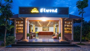 Een gebouw met een bord waarop 'Elwood' staat, en een receptiegedeelte met houten inrichting en een groot raam.