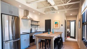 Een moderne keuken met roestvrijstalen apparatuur, een houten kookeiland met barkrukken en uitzicht op de eetruimte.