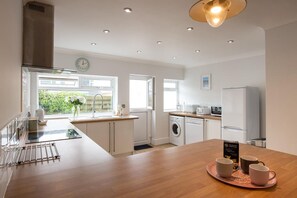 A modern kitchen with a central island, built-in appliances, and a view of greenery outside.