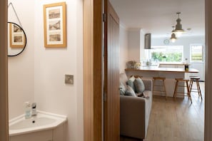 Hallway with coastal artwork leading through to the bright kitchen and family room, holiday home sleeping seven in Rhosneigr, Anglesey