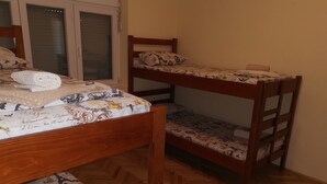 Ein Zimmer mit zwei Etagenbetten, Holzboden und einem Fenster mit Jalousien.
