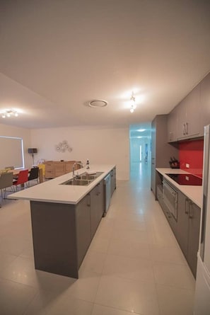 A modern kitchen with a central island, a dining area with chairs, and a view into another room.