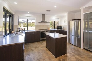 A modern kitchen with a central island, stainless steel appliances, and large windows. - House 19 - The Spice House Dunsborough (Dunsborough)