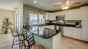 A kitchen with a large island, white cabinets, a microwave, and a ceiling fan.