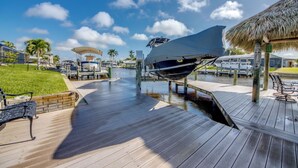 A boat docked at a pier with a thatched roof structure nearby.