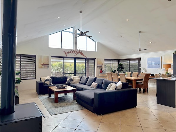 A spacious living area with a sectional sofa, a dining table with chairs, and a kitchen area. - House 23 - Seahorse Dunsborough (Dunsborough)
