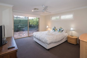 A bedroom with a bed, bedside lamps, a TV, and a ceiling fan. - House 20 - The Garden House Dunsborough (Dunsborough)