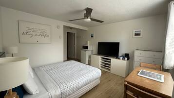 Una habitación de hotel con cama, escritorio, televisor, ventilador de techo y una pared con una cita motivacional.
