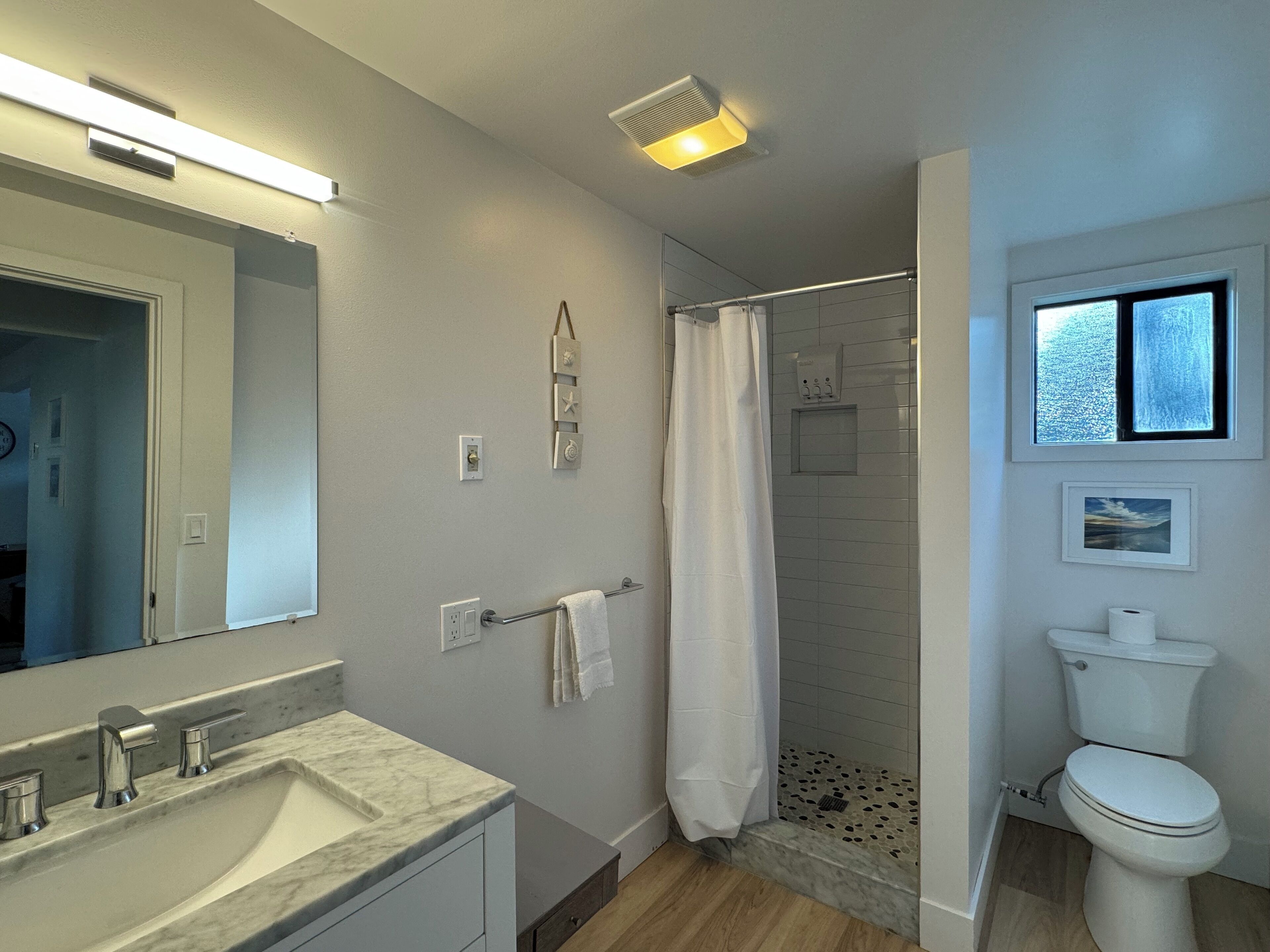 A modern bathroom with a marble sink, a glass shower enclosure, and a toilet.